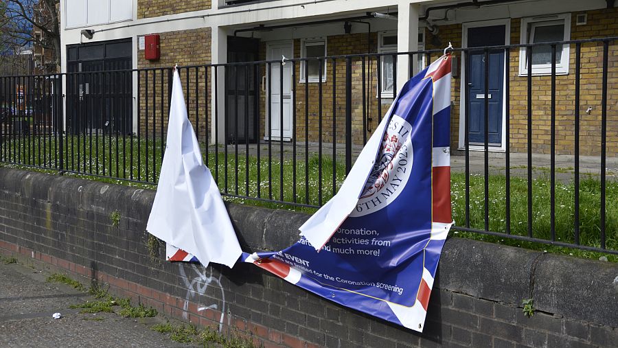 Un cartel anunciando la coronación de Carlos III partido por la mitad en el barrio londinense de Tower Hamlets