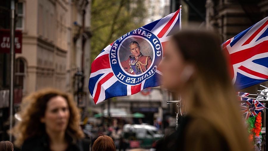 Varias personas pasan por un puesto que vende banderas que anuncian la coronación de Carlos III en Londres