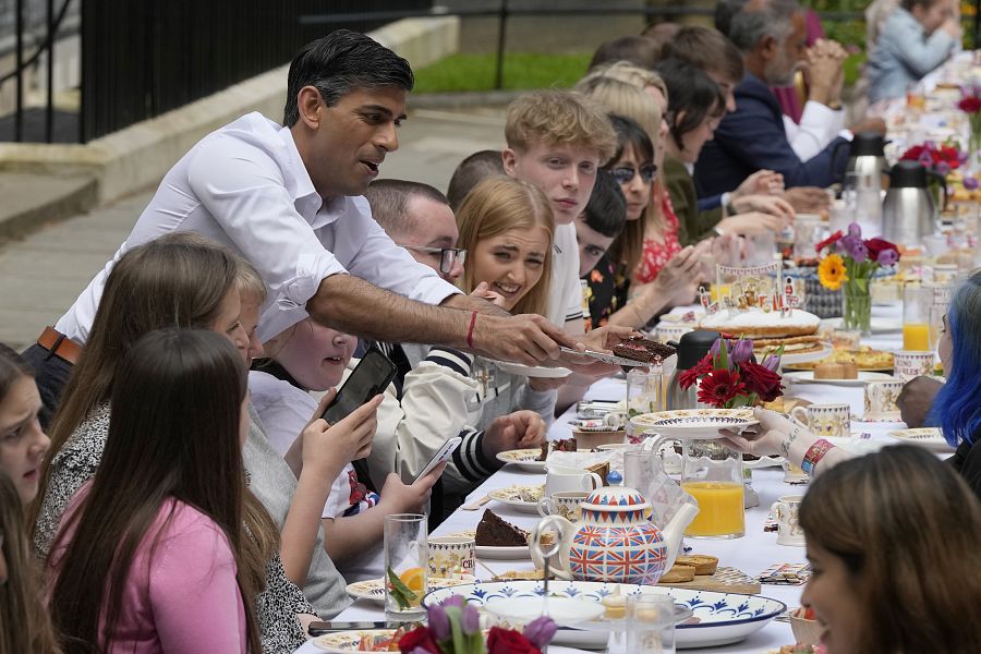 El primer ministro, Rishi Sunak, entrega un trozo de tarta a un invitado durante su asistencia a la fiesta del Gran Almuerzo en Downing Street