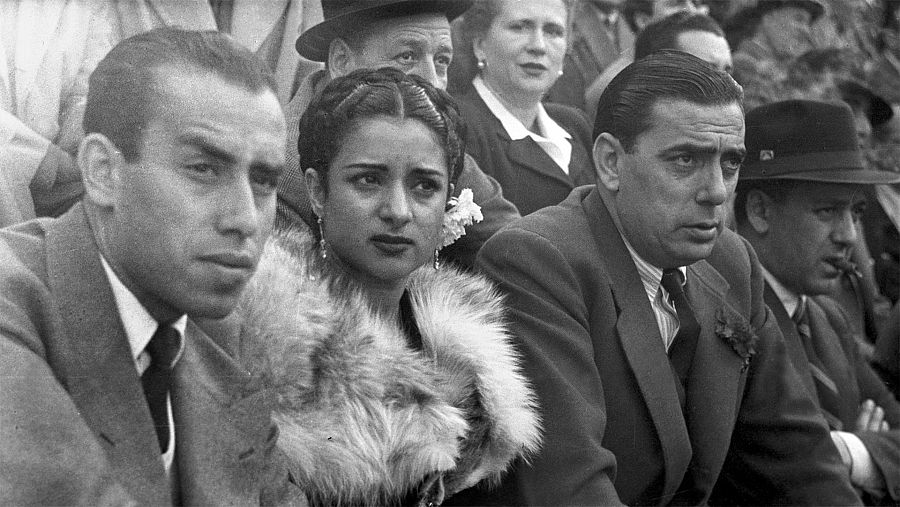 Imagen en blanco y negro de Lola Flores y Manolo Caracol sentados en el tendido de una plaza de toros