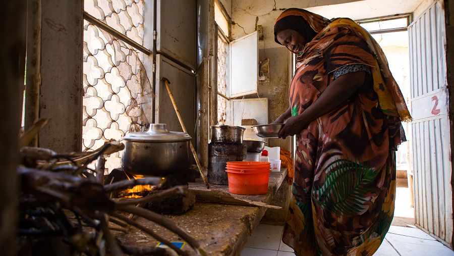 Una madre desplazada prepara comidas para familias en un albergue temporal en Sudán