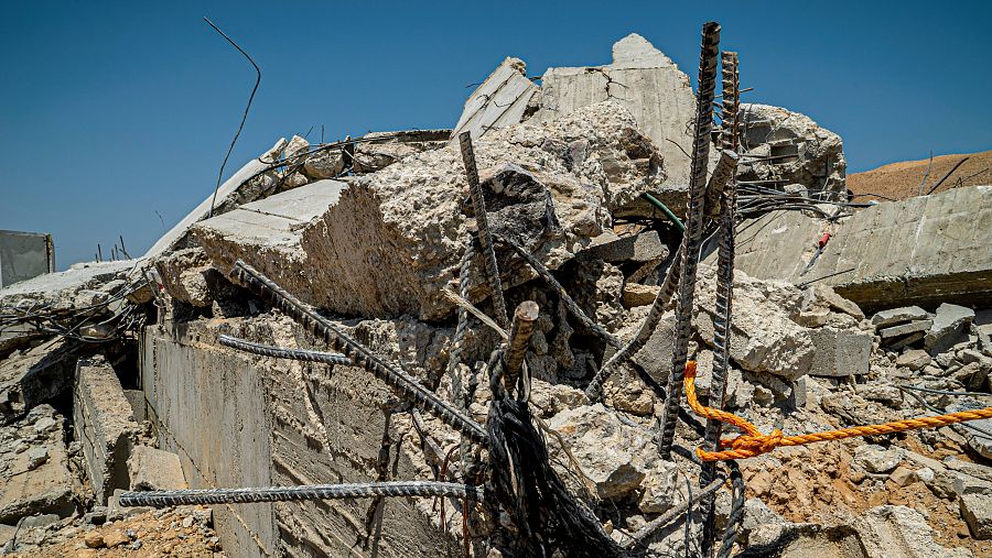 Ruinas de una casa en detalle con hierros retorcidos y piedras rotas.