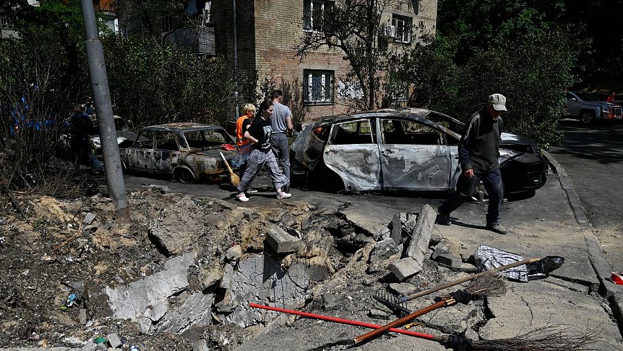 Varias personas inspeccionan sus coches dañados tras un ataque con drones del ejército ruso