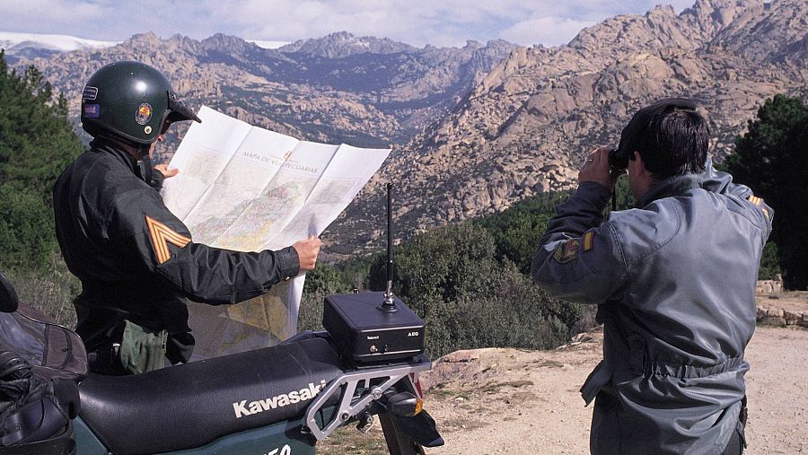 Dos agentes del SEPRONA de espaldas en un monte. Uno de ellos, consultando un plano.