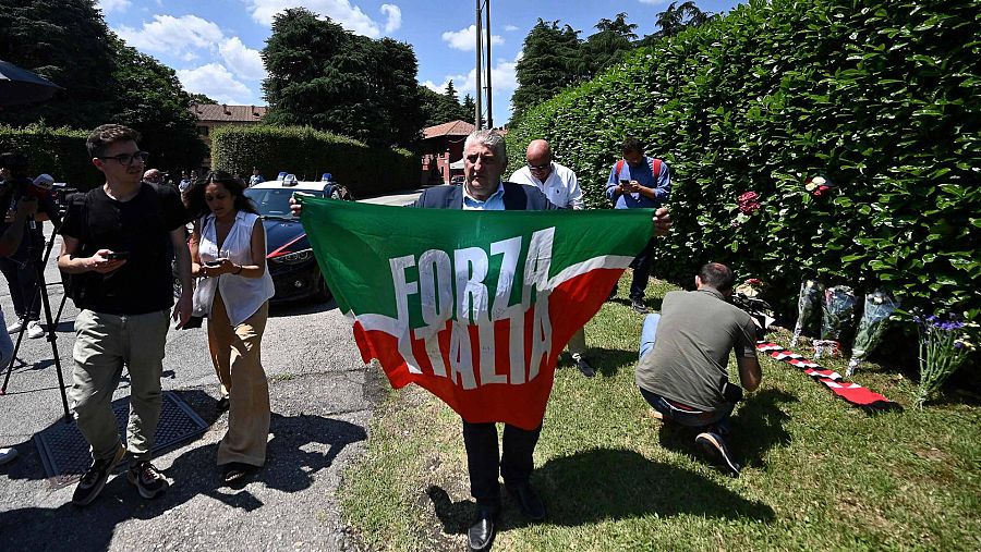 Un seguidor de Berlusconi y de su partido, Forza Italia, ondea la bandera fuera de la residencia del ex primer ministro en Villa San Martino, en Arcore, norte de Italia. Foto: Piero CRUCIATTI / AFP