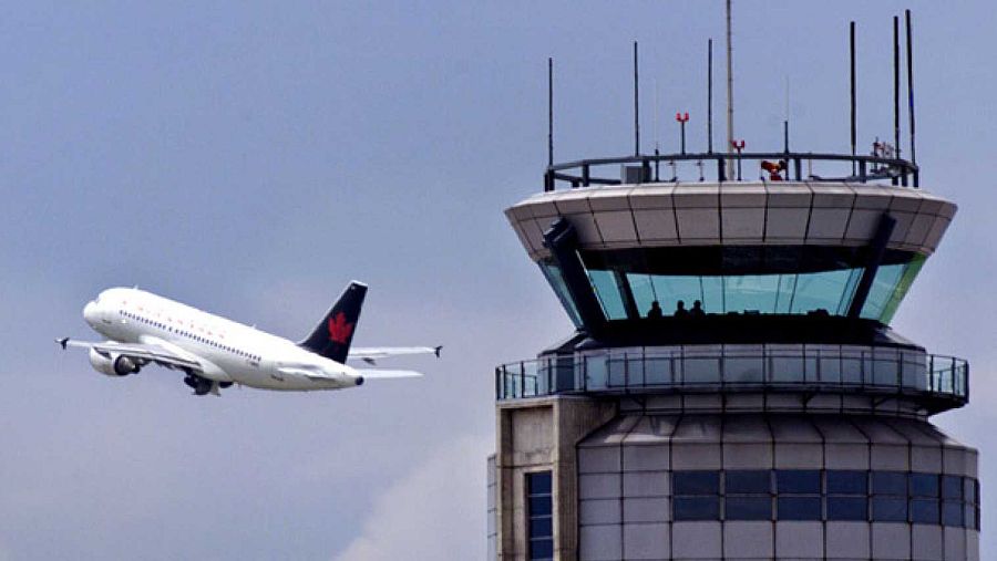 Un avión sobrevolando la torre de control de un aeropuerto