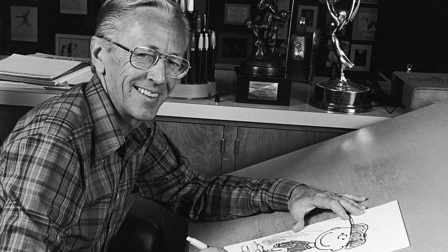 Imagen en blanco y negro del dibujante y guionista Charles Schulz abocetando a Charlie Brown