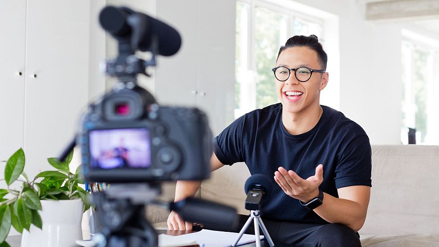 Un joven influencer graba un vídeo para redes sociales con una cámara.