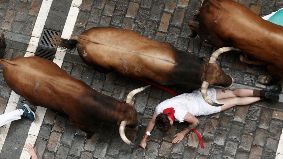 Los toros de La Palmosilla pasan por encima de un mozo a su paso por la calle de la Estafeta en el primer encierro de los Sanfermines 2023.