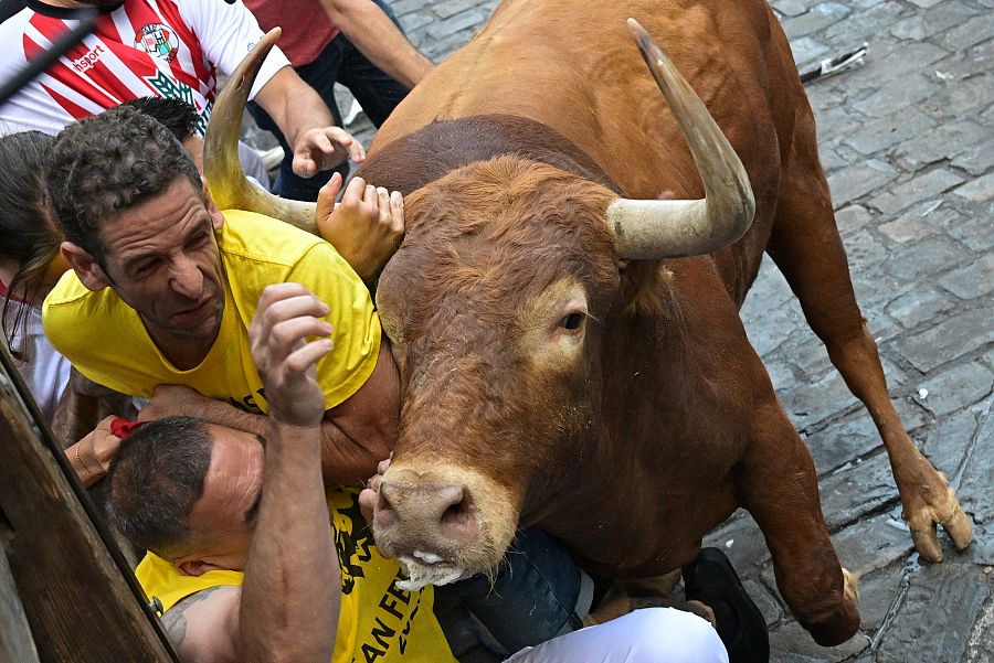 Un toro embiste a un grupo de corredores durante el tercer encierro de los sanfermines 2023