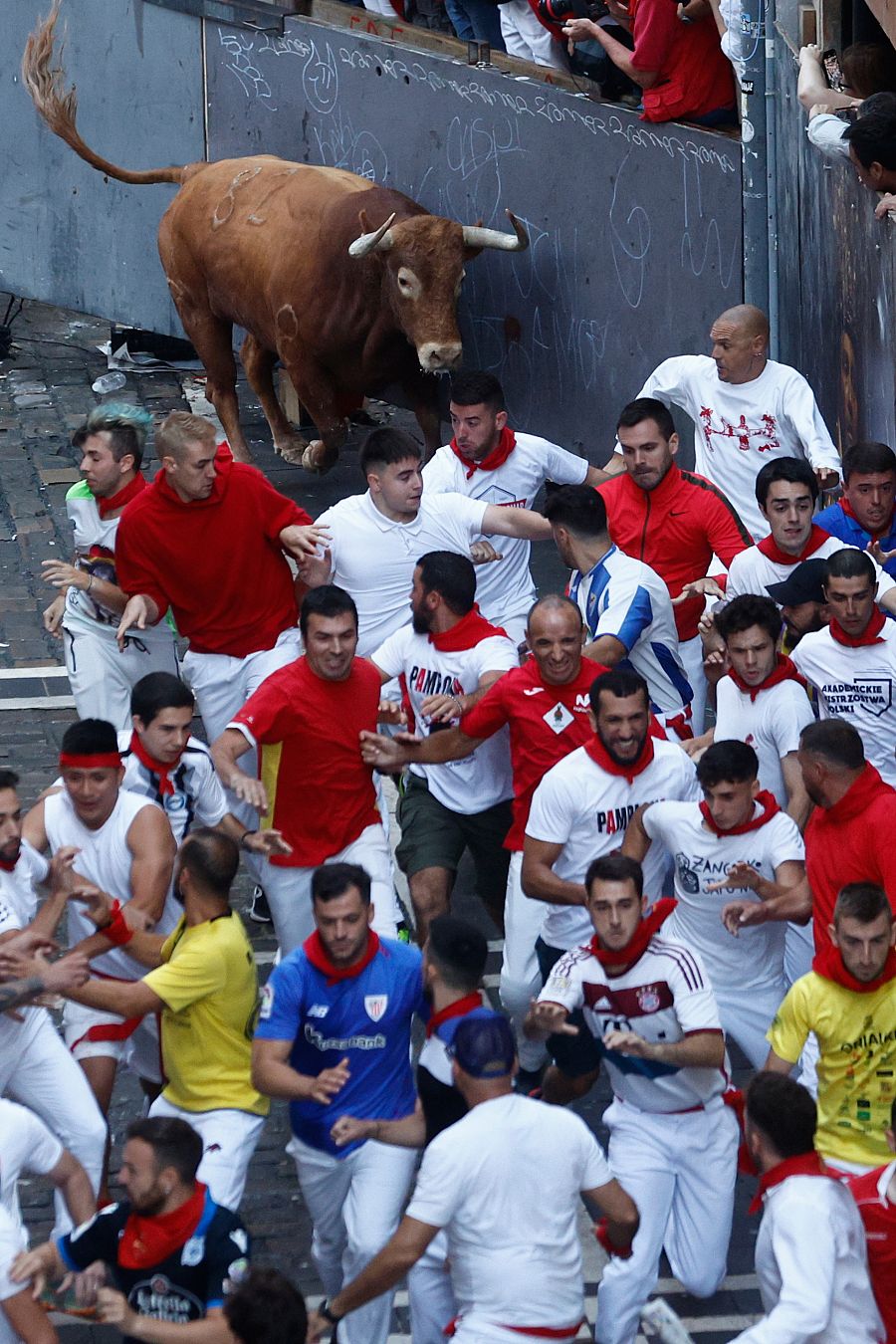 Los toros de la ganadería de Cebada Gago a su llegada a la curva de Mercaderes para enfilar Estafeta durante el tercer encierro de los sanfermines 2023.