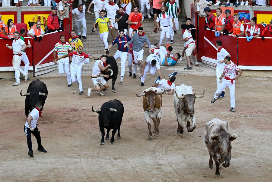 Un mozo es arrollado por uno de los toros de la ganadería de Fuente Ymbro en su entrada a la plaza de toros de Pamplona durante el cuarto encierro de los sanfermines 2023