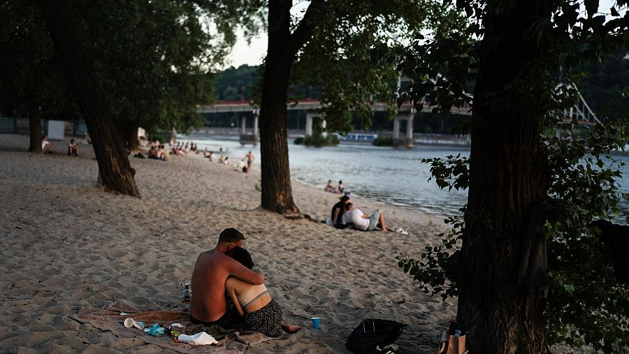 Una pareja se abraza en la playa a lo largo del río Dniéper en Kiev