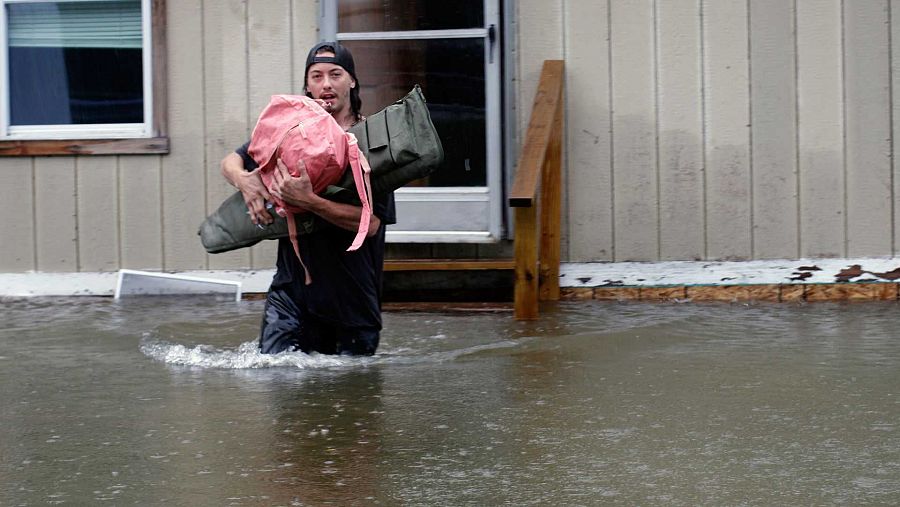 Un hombre lleva sus pertenencias a través de las aguas en una inundación en Bridgewater, Vermont.