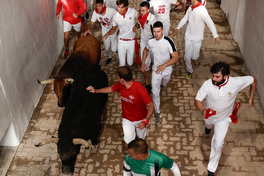 Los mozos acceden a la plaza perseguidos por toros de la ganadería extremeña Jandilla, durante el sexto encierro de Sanfermines