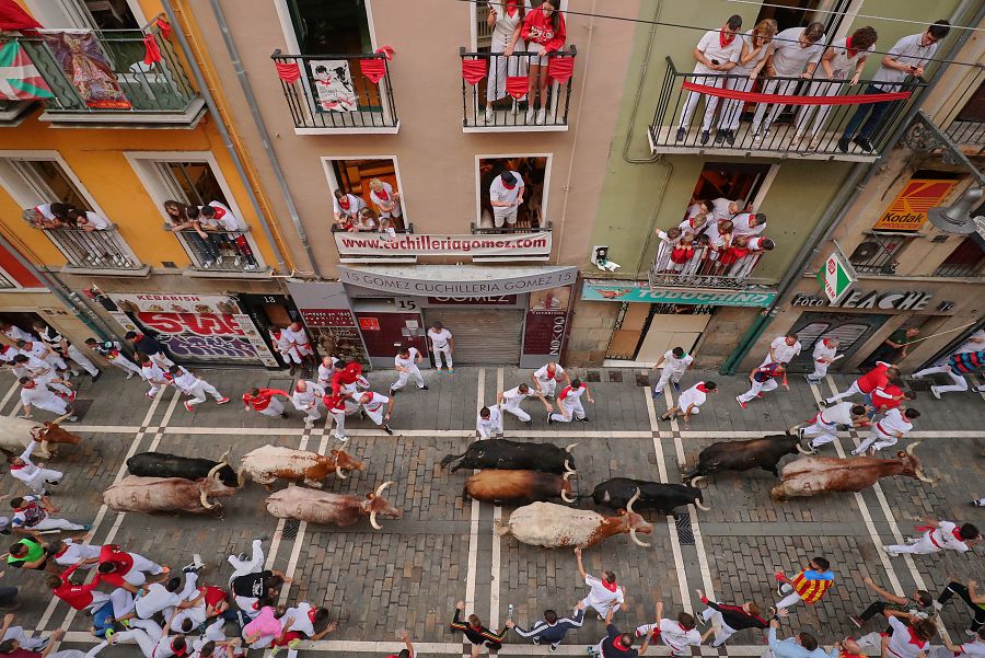 Mozos perseguidos por toros de la ganadería extremeña Jandilla en el tramo que va desde la curva de Mercaderes al inicio de Estafeta, durante el sexto encierro de Sanfermines