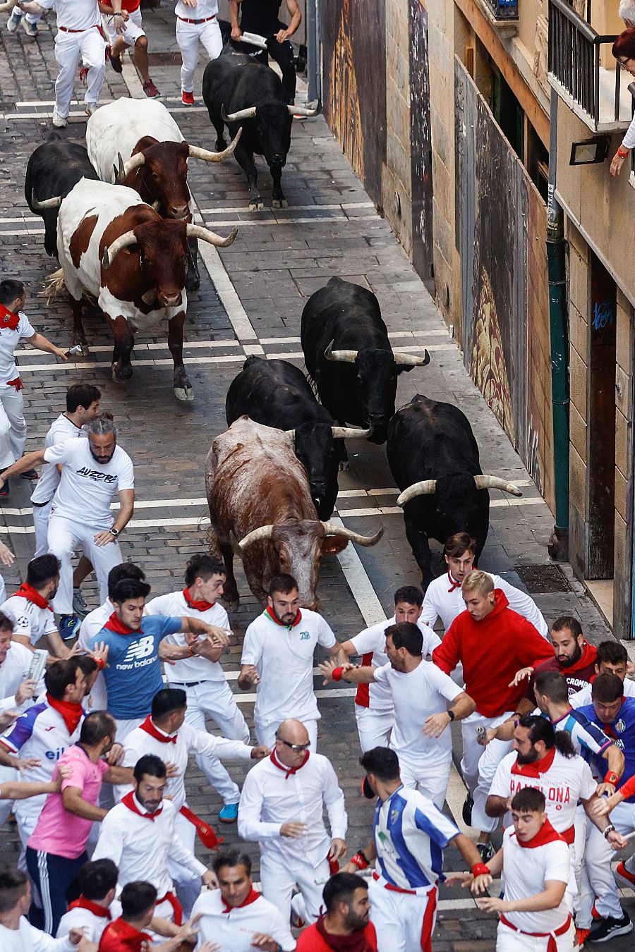 Mozos perseguidos por los toros en la calle Estafeta durante del séptimo encierro de los sanfermines 2023