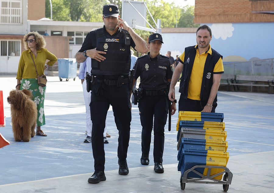 Un cartero que lleva votos por correo llega escoltado por dos agentes de la policía