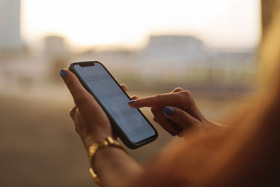 Mujer con móvil en la mano al sol