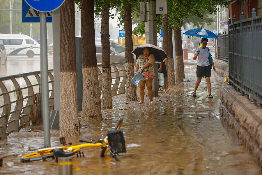 Una mujer transporta un contenedor de agua por un camino embarrado en el distrito de Mentougou,en Pekín.