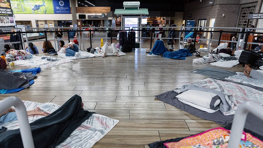 Mantas y telas en el suelo del aeropuerto dispuestas para dormir.