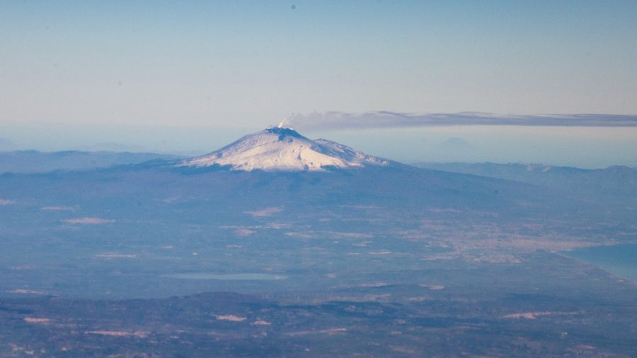 El Monte Etna humeando entre las cimas de la cadena montañosa en la que se encuentra.