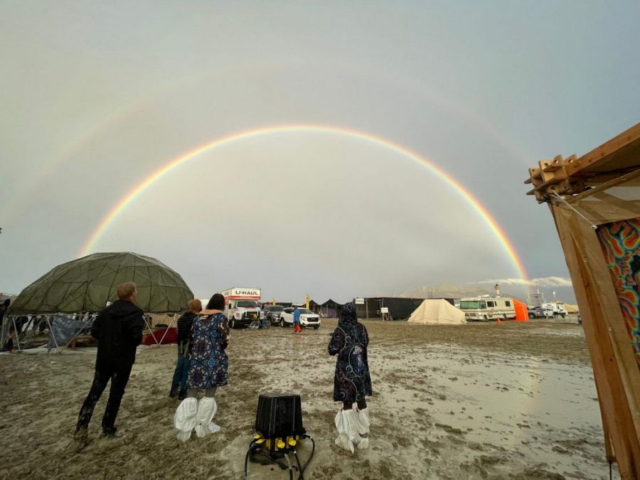 Los asistentes contemplan un arco iris sobre una llanura desértica inundada, después de que las fuertes lluvias convirtieran en un lodazal el festival Burning Man.