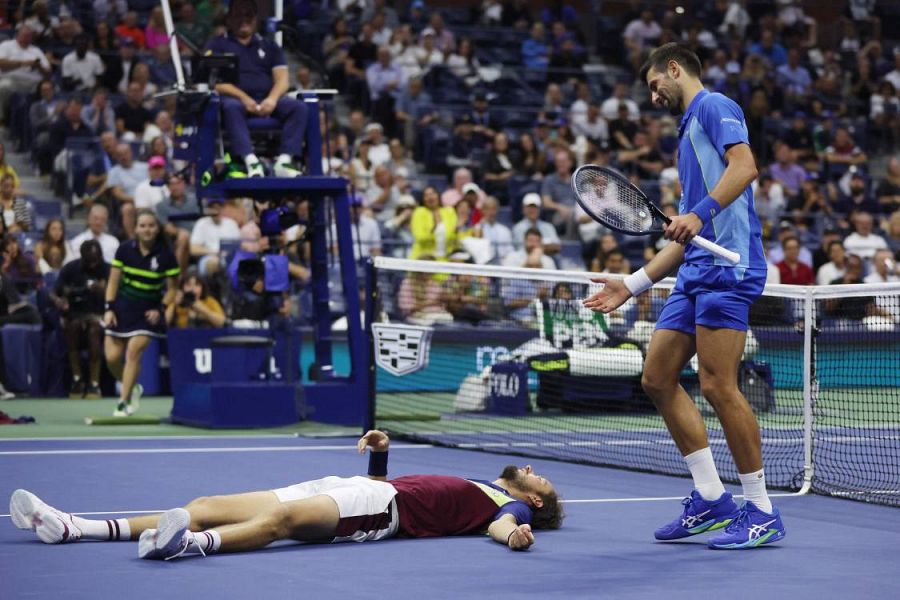 El tenista Novak Djokovic cruza la red para ayudar a Daniil Medvedev, que se cayó durante un punto en la final masculina del US Open 2023.