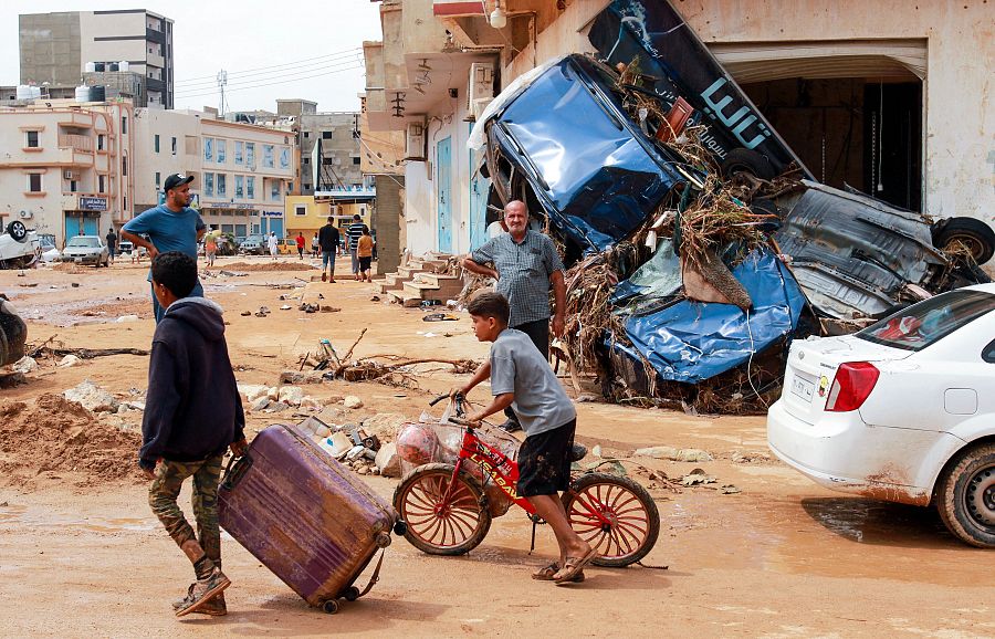 Un niño tira de una maleta entre los escombros en una zona dañada por las inundaciones