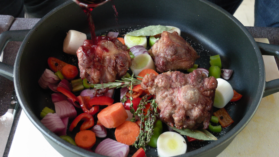 Poner en una bandeja de horno todas las verduras, las hierbas y añadir el rabo de toro. Incorporar el vaso de vino tinto, el de agua y meter al horno durante 2 horas.