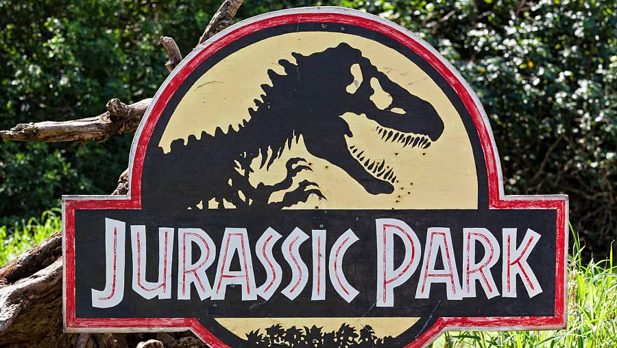 Cártel de la película de Parque Jurásico, escrito en inglés, bajo con la silueta de un esqueleto de dinosaurio