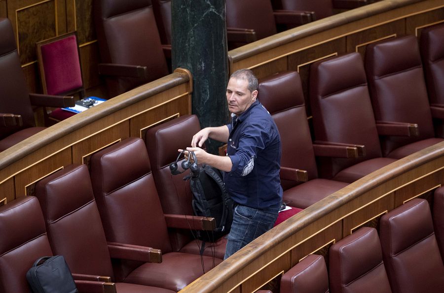 Una persona prepara los pinganillos para que los diputados puedan recibir la traducción simultánea de las lenguas cooficiales antes de la primera sesión del debate de investidura
