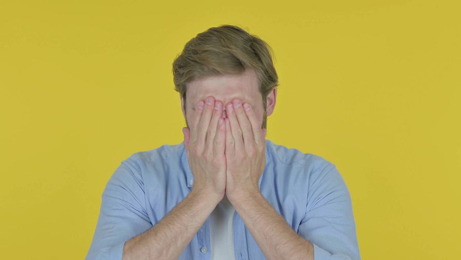 Un hombre tapa su rostro con las dos manos