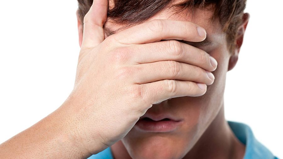 Un hombreo tapa su rostro con una mano