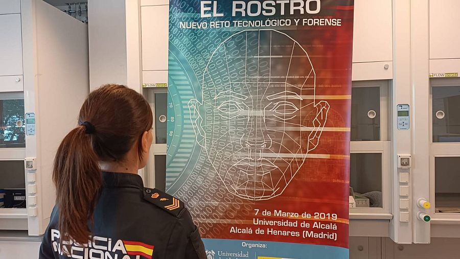 Una policía observa un cartel de reconocimiento facial