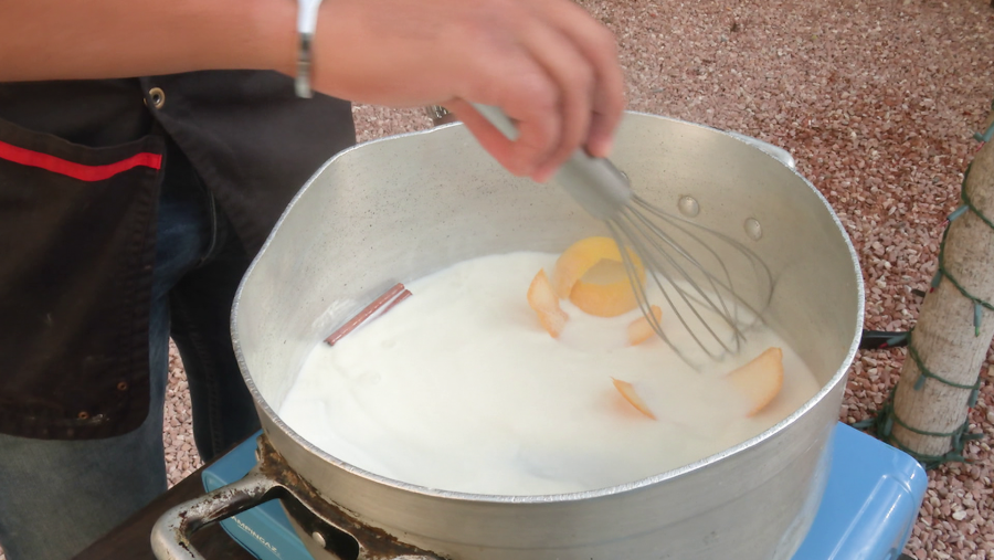 Poner la leche en la olla, después la canela, el limón y la naranja y se deja calentar a fuego bajo. Siempre removiendo para que no se cuaje.