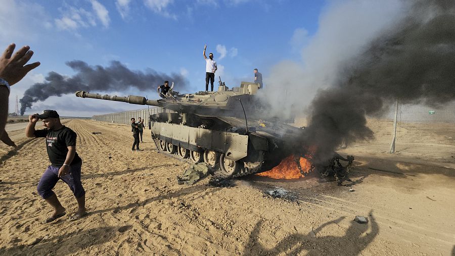Palestinos sobre un tanque israelí destruido en la Franja de Gaza.