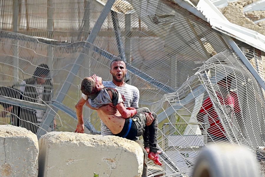 Un hombre coge a un palestino muerto en un ataque aéreo israelí en el cruce de Erez