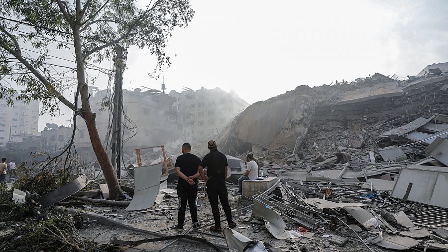 Ciudadanos palestinos frente a las ruinas de un edificio e Gaza
