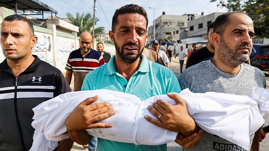 Imágenes del día 4 de la Guerra de Israel: Un hombre palestino lleva el cuerpo amortajado de un niño muerto en los ataques israelíes, en Khan Younis, en el sur de la Franja de Gaza.