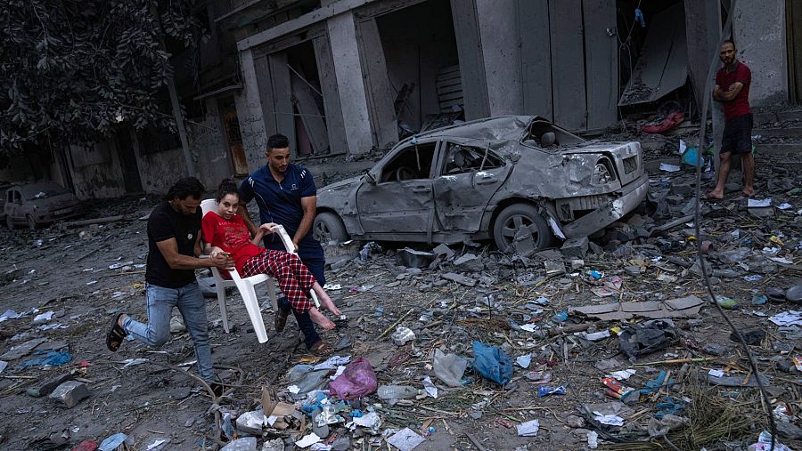 Imágenes del día 4 de la Guerra de Israel: Dos hombres transportan a una niña entre los escombros tras los ataques aéreos de Israel en la ciudad de Gaza.