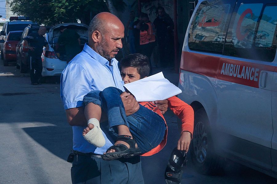 Un hombre corre con un niño en brazos herido por un misil israeli