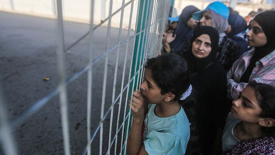 Varias personas esperan fuera del cruce fronterizo entre la Franja de Gaza y Egipto en Rafah