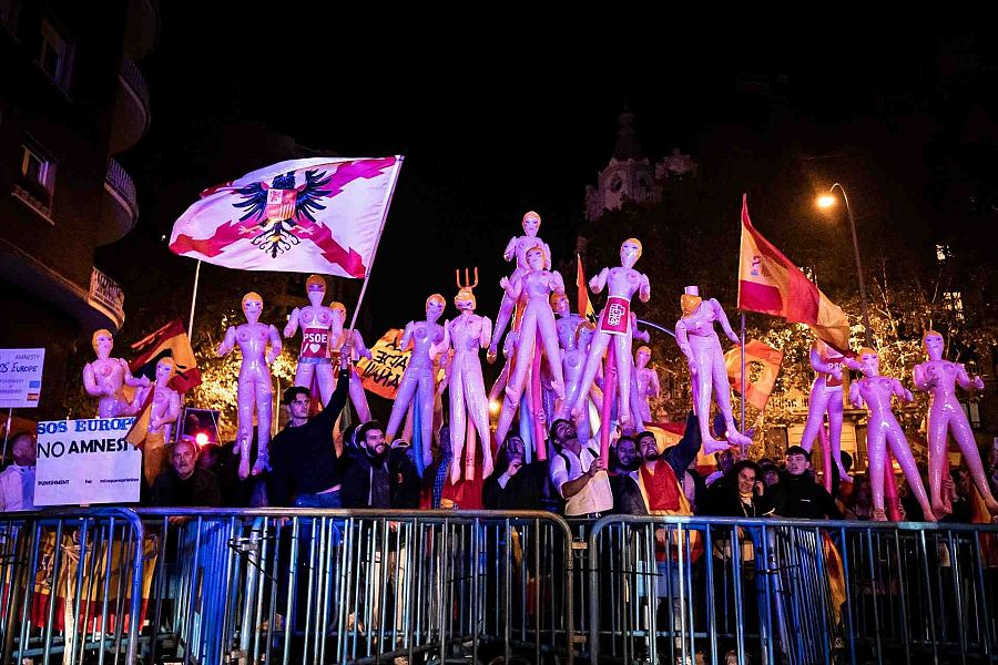 Varios manifestantes con muñecas hinchables y banderas durante una manifestación contra la amnistía frente a la sede del PSOE en Ferraz.