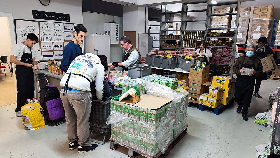 Personas organizando cajas de alimentos y productos de higiene en un almacén.