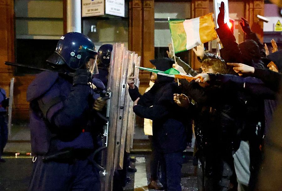 Varias personas se paran frente a la policía antidisturbios durante una manifestación tras un apuñalamiento que dejó cinco heridos en Dublín, Irlanda.