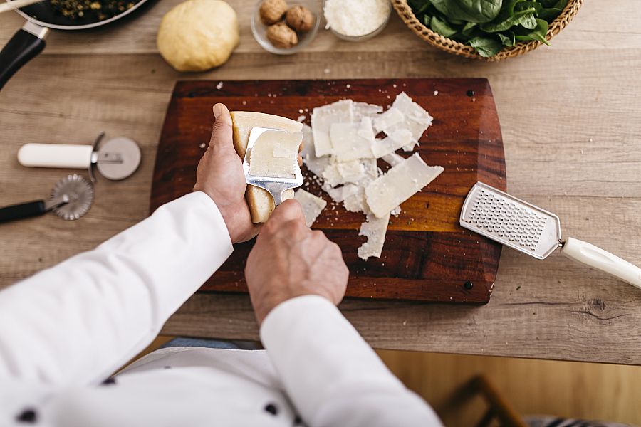 Chef preparing stuffing for ravioli, slicing parmesan cheese