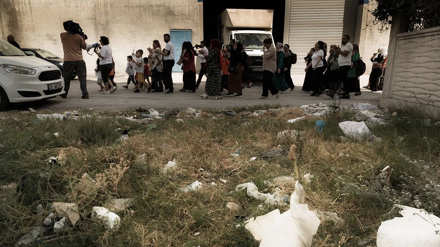 Persona con megáfono protesta por las calles de una barriada de Turquía con plásticos en primer término.