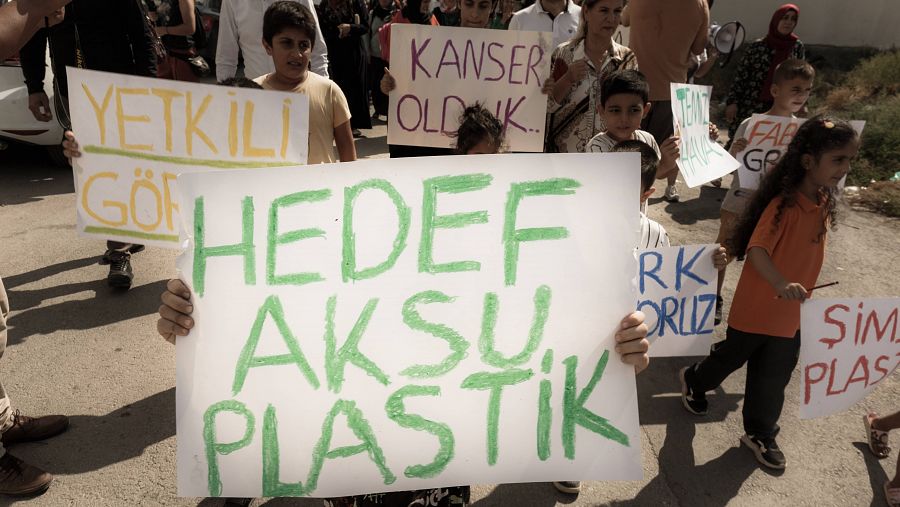Personas pobres y humildes portan carteles en una manifestación pidiendo el cierre de fábricas que contaminan.