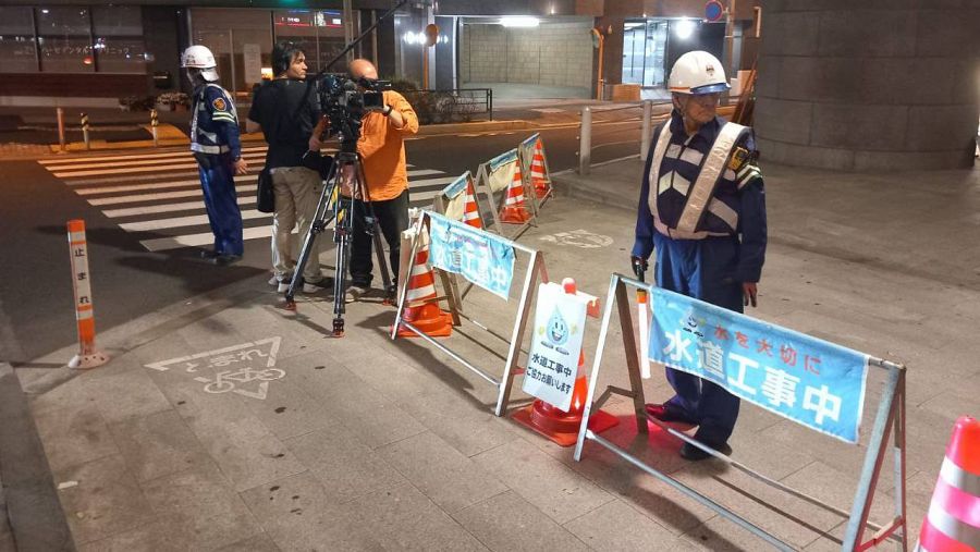 Un equipo de televisión graba de noche a dos obreros en la calle